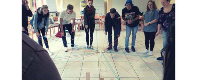Acht Freiwillige spielen gemeinsam ein Kooperationsspiel