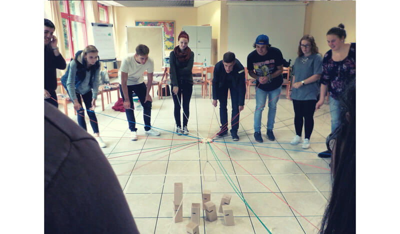 Acht Freiwillige spielen gemeinsam ein Kooperationsspiel