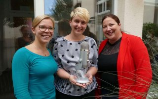 Annika Schäfer, Jennifer Letzelter mit Podcastmikrofon und Tamara Gassner lächeln in die Kamera;