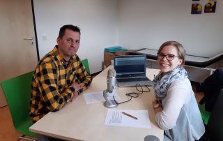 Annika Schäfer sitzt mit dem zu Interviewenden Herrn Prechtl an einem Tisch mit Mikrofon und Laptop