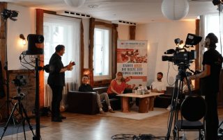 Der Moderator der Ehrung mit den Freiwilligen im Interview, gefilmt von einem Kameramann