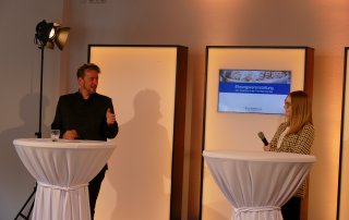 Moderator und zu Interviewende auf einer Bühne