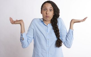 eine Frau zuckt mit den Achseln und wirkt überfragt