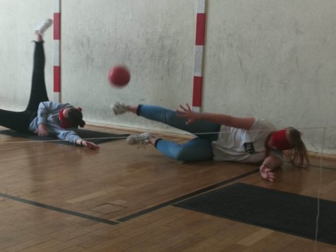Zwei Freiwillige spielen Blindentorball. Beide werfen sich auf den Boden, während der Ball auf sie zufliegt.