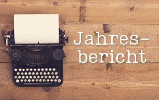 Eine Schreibmaschine auf einem Holztisch, daneben der Titel "Jahresbericht"